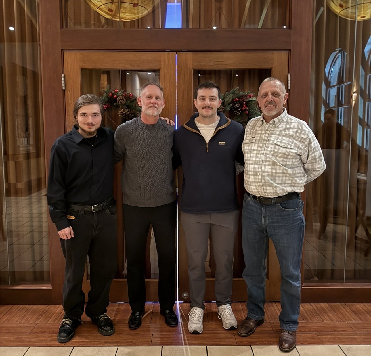 The DE Plumbing team — four team members standing together