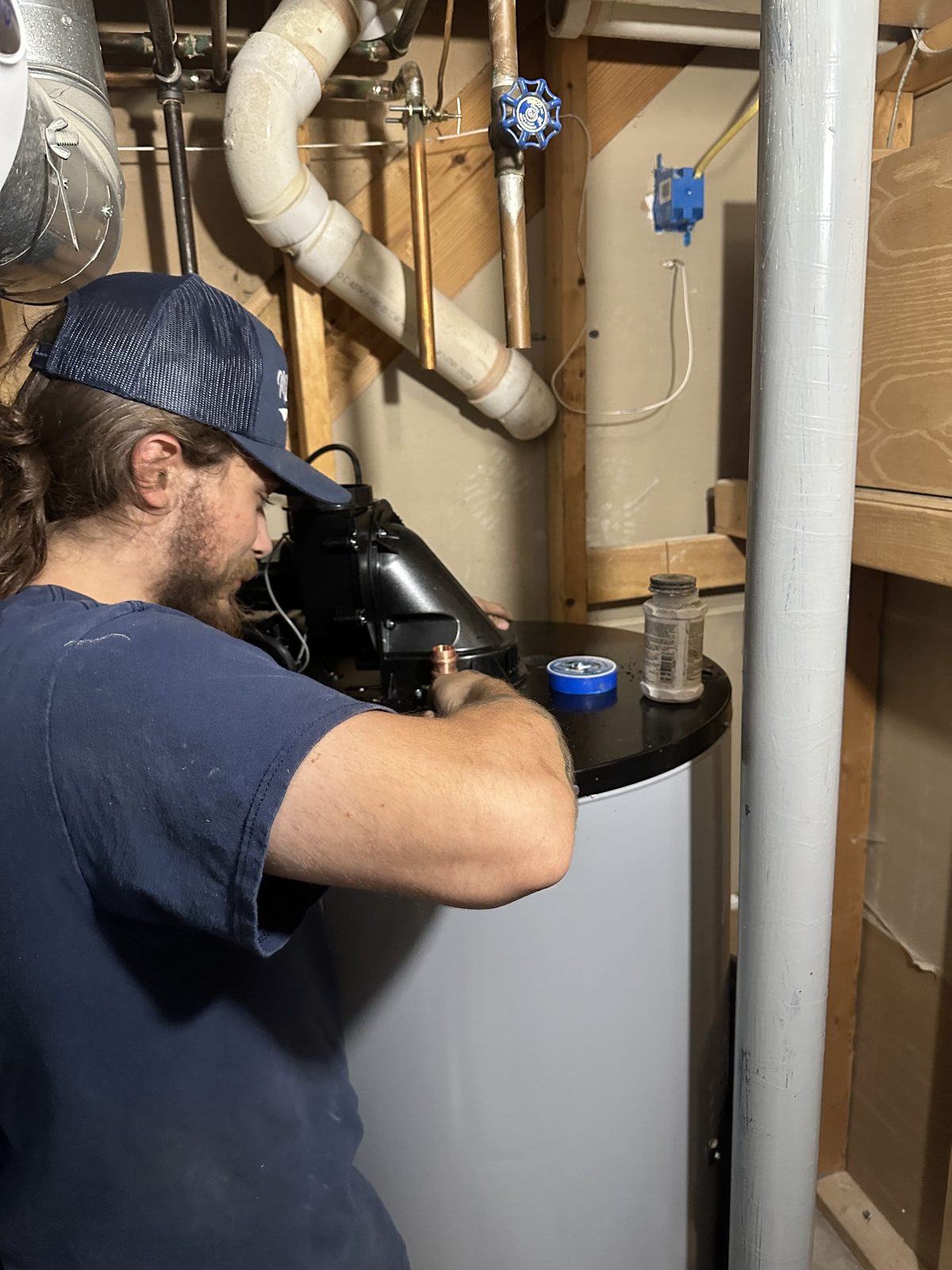 DE Plumbing technician Isaiah working on a water heater — Cincinnati